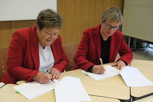 Bildungsstaatssekretärin Bettina Brück und PL-Direktorin Dr. Birgit Pikowsky am Tisch sitzend bei der Unterzeichnung der Ziel- und Leistungsvereinbarung